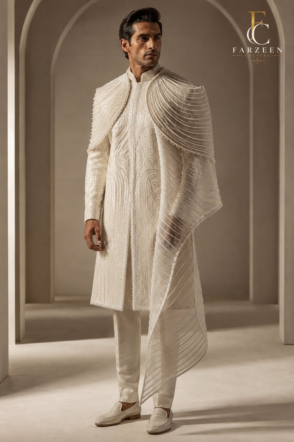 Groom in a pearl silk ensemble with a sculpted organza mantle
